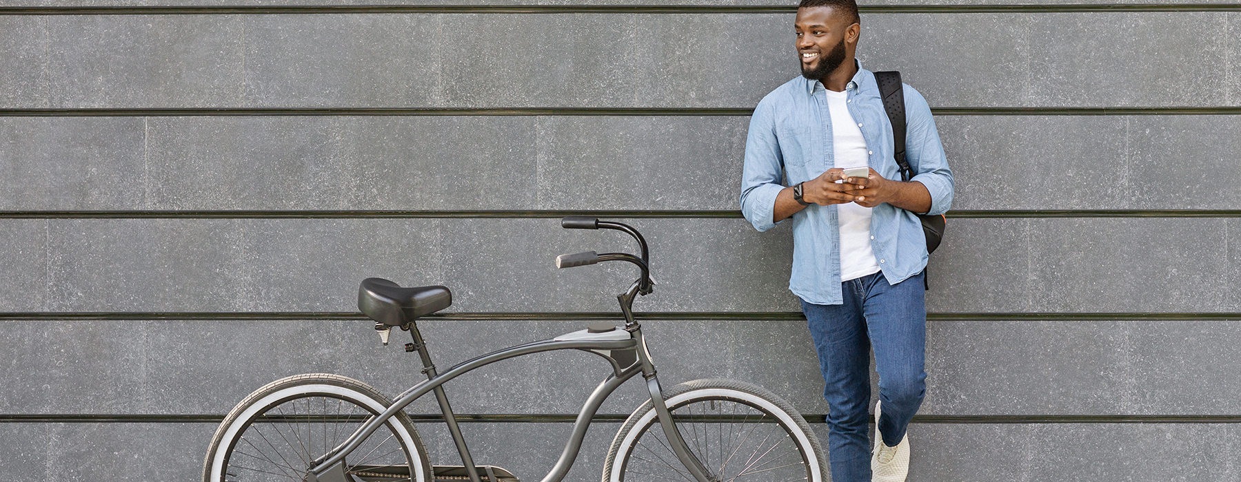 A man is leaning against the wall with his bike next to him 